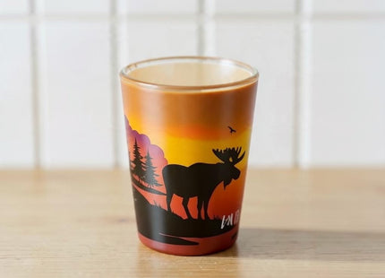Maine Shot Glass - Sunrise — small empty souvenir shot glass in a cottage setting, Seasonal Maine logo